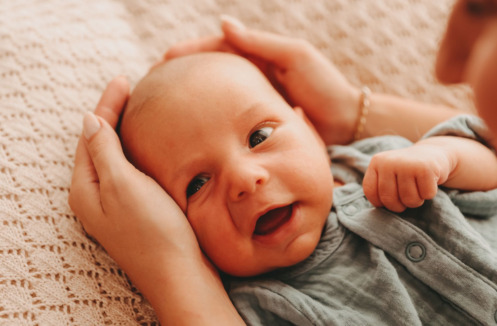 Baby in Schlafsack. Mutter umfasst seinen Kopf. Welcher Baby-Schlafsack eignet sich bei welcher Temperatur?